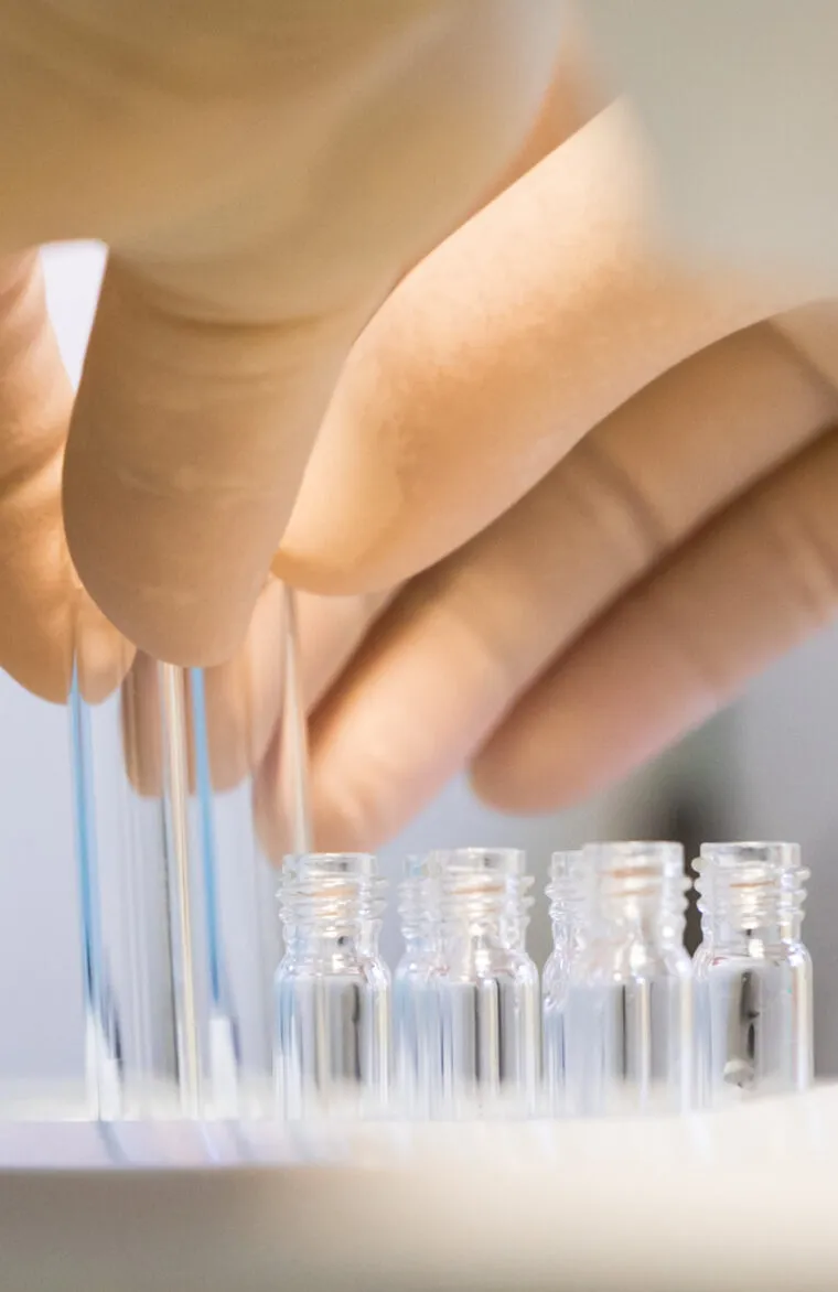 Pharmaceutical researcher handling glass vials in a laboratory