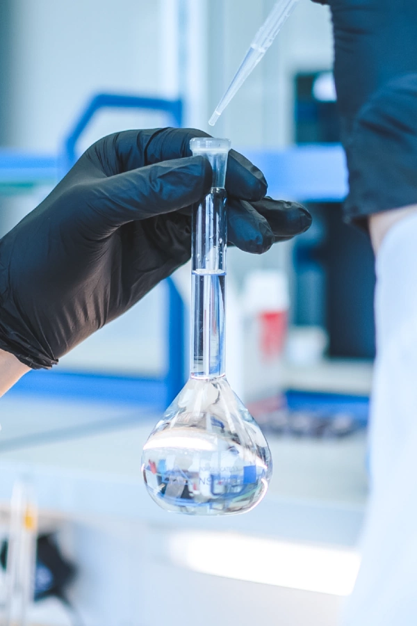 Pharmaceutical researcher filling a glass flask in a Kalceks laboratory