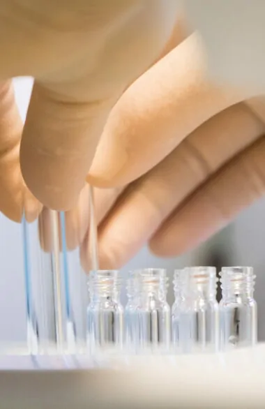 Pharmaceutical researcher handling glass vials in a laboratory